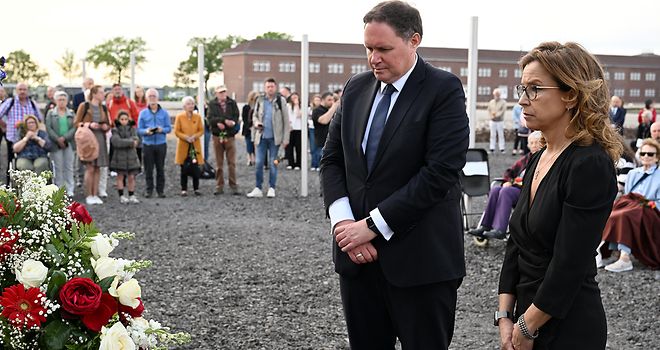 Carola Veit und Dr. Carsten Brosda stehen vor einigen Blumen und gedenken des KZ Neuengamme.